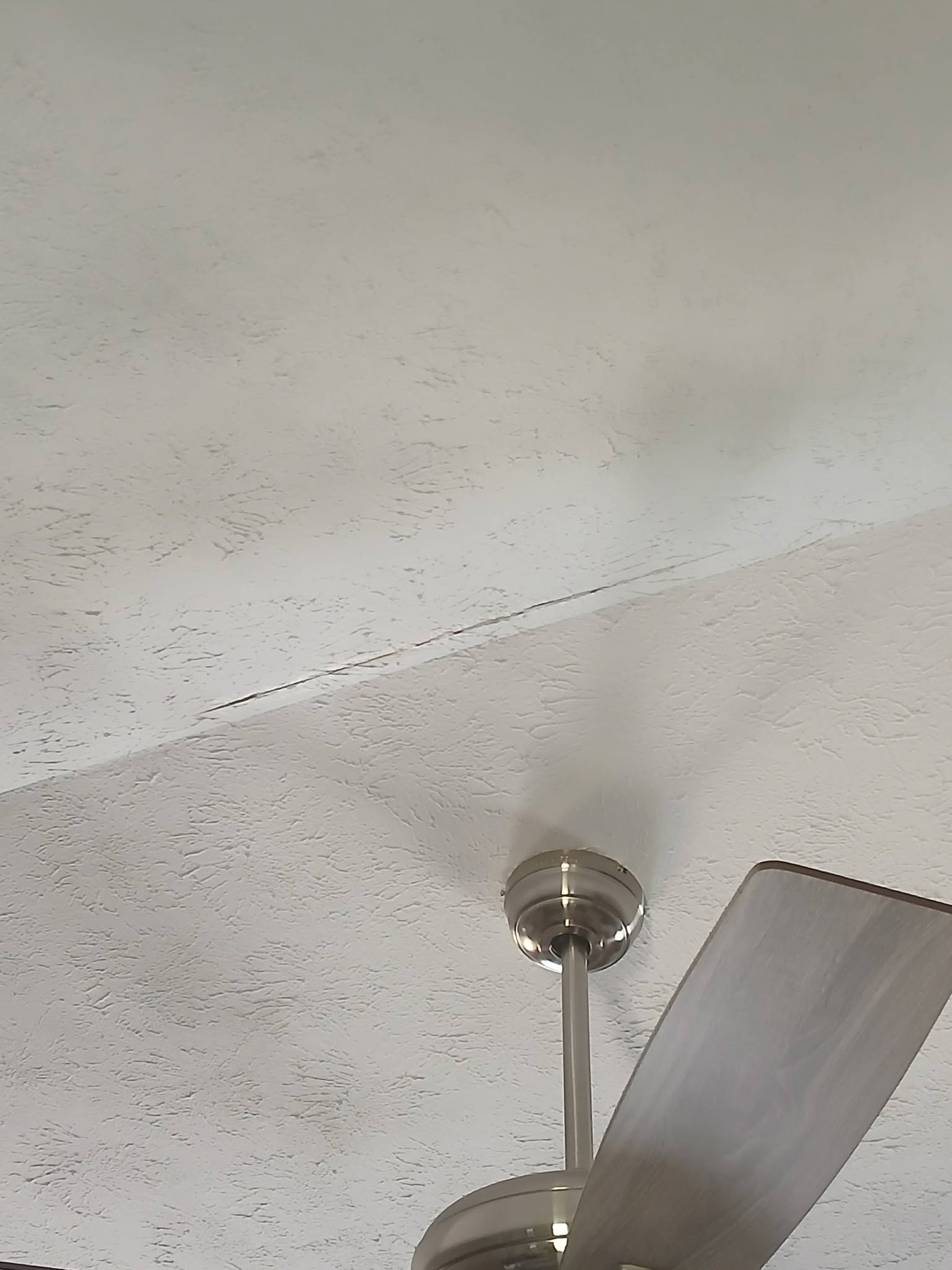 Cracked ceiling seam near a light fixture before repair